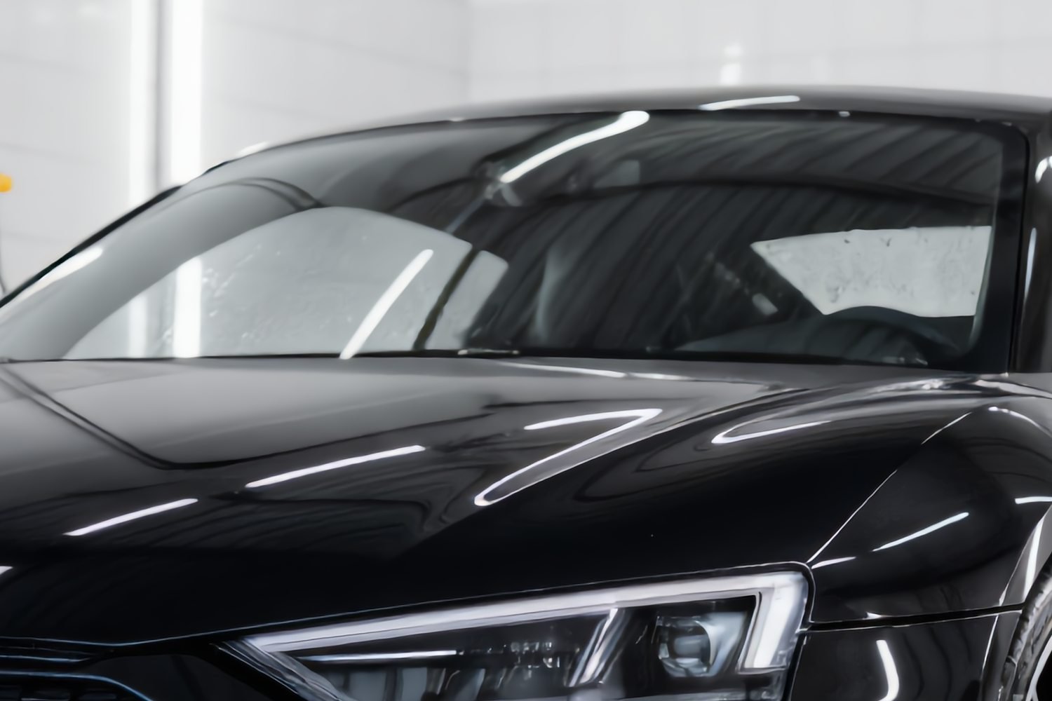 Kraakheldere voorruit en spiegelende motorkap van een zwarte Audi na glas- en teflon coating